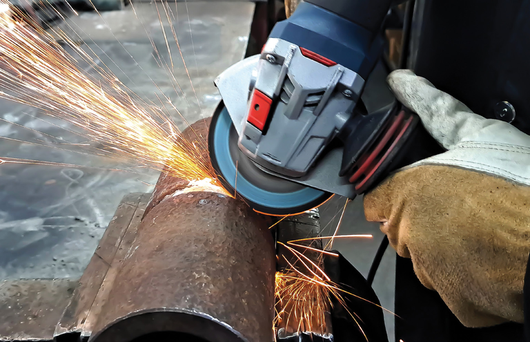 Angle grinder cutting a metal pipe with sparks flying