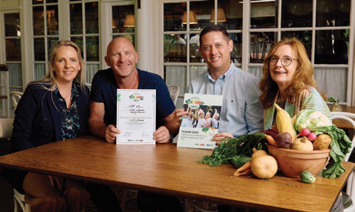 Chef Matt Moran AM signing the Pledge for More Veg with three colleagues around a table of vegetables