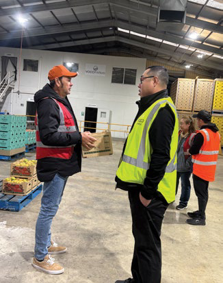 Man in high-vis vest talking with worker at packing facility