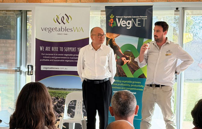 Two men speaking at the roadshow event, standing beside vegetablesWA and VegNET banners