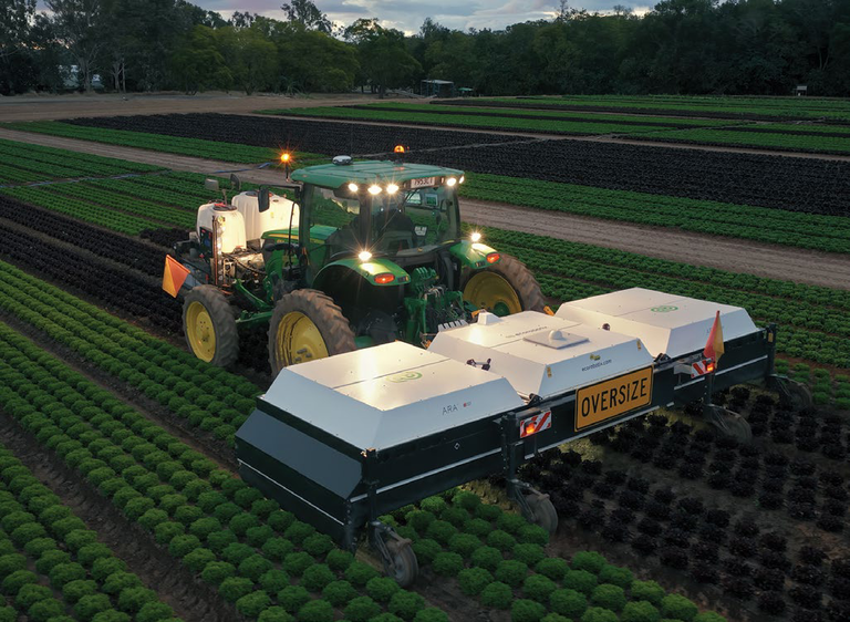 Aerial view of the Ecorobotix ARA Ultra High Precision Sprayer towed by a tractor through rows of lettuce crops