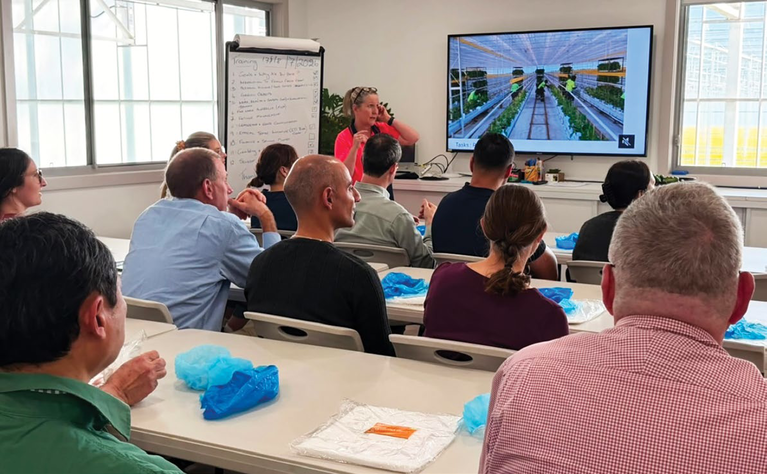 Training session with growers, food safety professionals and delegates in a classroom watching a screen with a greenhouse simulation