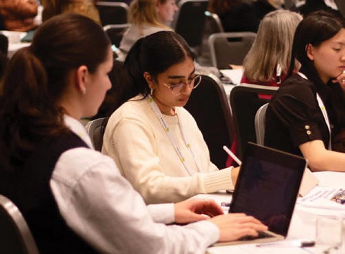 Attendees seated at tables taking notes during the symposium