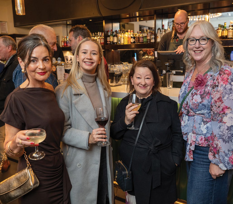 Guests at a bar event holding drinks and smiling