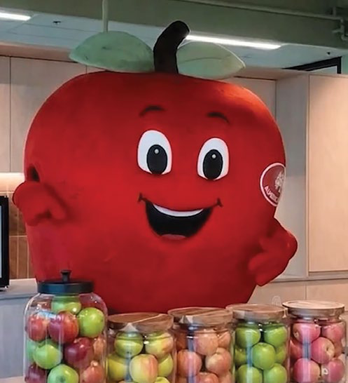 Appy the apple mascot with jars of apples