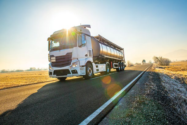 Truck driving on a rural road at sunrise