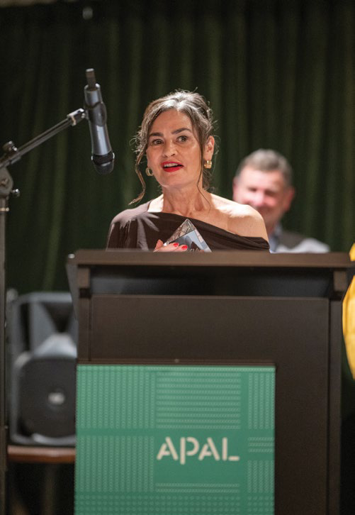 Nardia Stacy speaking at a podium with APAL branding